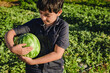 © Si And Si/ADDICTIVE STOCK - Positive preteen boy holding ripe watermelon in green garden in summer day in countryside