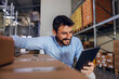 © Dusan Petkovic - Smiling attractive bearded supervisor crouching next to boxes and using tablet to check on goods.