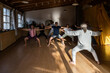 © David Fuentes/ADDICTIVE STOCK - Full body back view of mature male instructor demonstrating technique of chi kung exercise for group of people during practice in studio