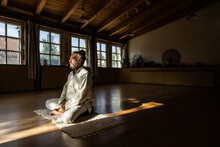 Senior Man Practicing Chi Kung Meditation In Lotus Position In Studio