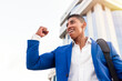 © Jose Carlos Gutierrez/ADDICTIVE STOCK - Low angle of cheerful young African American male manager in formal blue suit celebrating successful deal while standing against modern city building