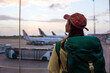 © Juan Alberto Ruiz/ADDICTIVE STOCK - Back view of young Asian female traveler with backpack standing near window in airport terminal and observing airplanes while waiting for flight in Sri Lanka