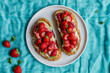 © Leire Gamboa/ADDICTIVE STOCK - Top view of yummy sweet bread toasts with fresh chopped strawberries and honey served on plate on blue tablecloth