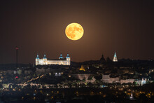 Amazing View Of Bright Full Moon In Dark Night Sky Over Old Town With Glowing Historical Palace