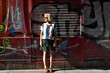 © Sofia Roncero/ADDICTIVE STOCK - Content female wearing trendy clothes standing near wall with graffiti and looking away while enjoying weekend in city