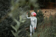 © Sergey Mironov/ADDICTIVE STOCK - Happy young red haired female astronaut in silver suit and glass sphere helmet looking away while walking in field near forest in summer day