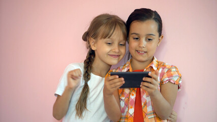 Wall Mural - Happy little girls with a smartphone in hands communicate at home with loved ones using modern technology