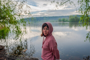 Wall Mural - a young woman in a sweater stands by the lake
