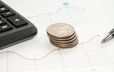 Business and Finance Concept: Stacked gold coins, calculator, pen on graphic chart