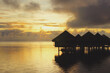 © Per Swantesson/Stocksy - Tahitian luxury bungalows on the ocean, at sunset