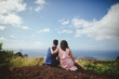 © Rob and Julia Campbell/Stocksy - Young couple sitting and cuddling together on hilltop enjoying each other and view