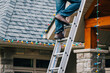 © Jen Grantham Photography/Stocksy - Man climbing ladder to hang up Christmas lights.