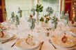 © Jess Craven/Stocksy - Simple blush pink roses and greenery in glass vases wedding decor table setting