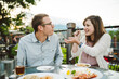 © Kate Daigneault/Stocksy - Young couple on a dinner date at a fancy outdoor restaurant.
