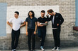 © Jesse Morrow/Stocksy - diverse group of four friends who are in a band stand against wall for promo photos