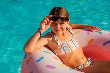 Sticker - adorable little girl playing in the pool with her inflatable donuts