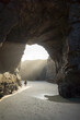 © ACALU Studio/Stocksy - Woman inside a cave looking at the sun at the beach