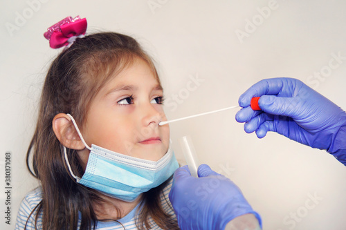 Screening virus, doctor taking nasal mucus test sample from nose performing respiratory virus testing procedure. Checking nasal cavity in ENT. girl in a protective face mask at doctor\'s appointment.