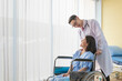 © Avirut S. - Young Doctor talking to woman in wheelchair after an operation. Smiling doctor looking at a female patient on a wheelchair in hospital. Photo of positive doctor and patient on wheelchair.
