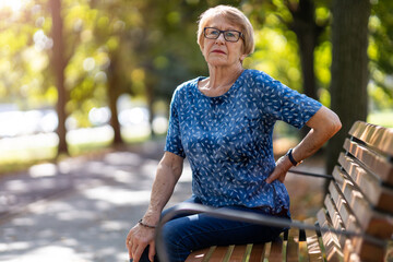 Wall Mural - Senior woman with back pain having difficulty to get up from the bench
