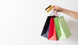 © Inna Dodor - Woman hand holding group of colorful paper shopping bags and credit card over white background.
