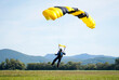 Closeup of a man parachuting near the ground with a yellow parachute during daylight