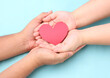 hands holding paper red heart on blue background,Concept of health in the family.