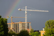Construction cranes and a rainbow in the sky