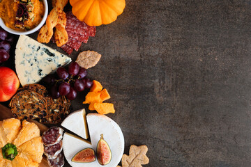 Wall Mural - Autumn charcuterie side border against a dark stone background. Variety of cheese and meat appetizers. Copy space.