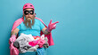 © wayhome.studio  - Studio shot of shocked bearded man in hero costume points on blank space for your advertisement poses against basin full of laundry isolated on blue background. Cleaning service and household