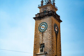 Wall Mural - Close up. The tower of the vintage Italian cathedral made of stone bricks with golden details, a wide clock, metal statues & sculptures in Bergamo, Lombardy, Italy. Old European architecture