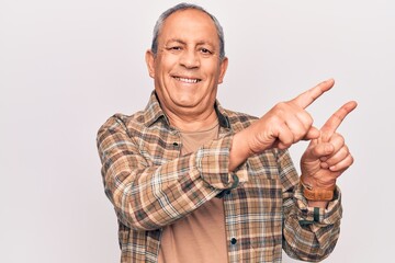 Senior man with grey hair wearing casual shirt smiling and looking at the camera pointing with two hands and fingers to the side.