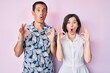 © Krakenimages.com - Beautiful couple wearing casual clothes looking surprised and shocked doing ok approval symbol with fingers. crazy expression