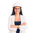 © Krakenimages.com - Young beautiful latin girl wearing architect hardhat and glasses happy face smiling with crossed arms looking at the camera. positive person.