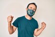 © Krakenimages.com - Middle age hispanic man wearing covid-19 protection mask very happy and excited doing winner gesture with arms raised, smiling and screaming for success. celebration concept.
