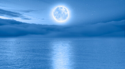 Full moon rising over empty ocean at night 