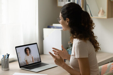 Poster - Happy Caucasian young woman sit at desk at home talk speak on video call on laptop with biracial friend. Smiling millennial female have webcam online lesson or conference with tutor on computer.