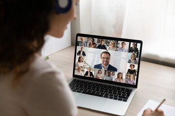 Wall Mural - Rear close up view of female employee have webcam digital virtual conference or meeting on laptop with diverse colleagues. Woman talk speak on video call on computer, engaged in online briefing.