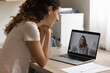 © fizkes - Smiling young woman look at laptop screen talk on video call with girlfriend at home. Happy millennial Caucasian female have pleasant webcam digital virtual conference or conversation on computer.