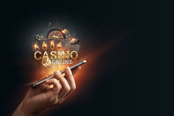 In a man's hand a smartphone with playing cards roulette and chips, black-gold background. Concept of online gambling, online casino. Copy space