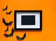 © svetlana_nsk - Mock up black frame with bats on orange background . Halloween party greeting card mockup with copy space. Flat lay, top view.