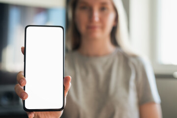 Wall Mural - young woman show smartphone with white screen indoor with sunlight from window