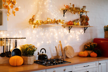 Autumn kitchen interior. Red and yellow leaves and flowers in the vase and pumpkin on light background