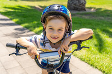 Portrait Of Cheerful Cute Kid With Helmet Riding His Bike At The Park