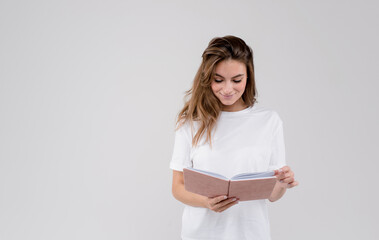 Wall Mural - Image of beautiful brunettewoman wearing white t-shirt making notes in diary book isolated over white background