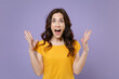 © ViDi Studio - Shocked amazed surprised excited young brunette woman 20s wearing basic yellow t-shirt spreading hands keeping mouth open looking camera isolated on pastel violet colour background, studio portrait.