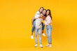 © ViDi Studio - Full length portrait of smiling funny young parents mom dad with child kid daughter teen girl in t-shirts giving piggyback ride to joyful sit on back isolated on yellow background. Family day concept.