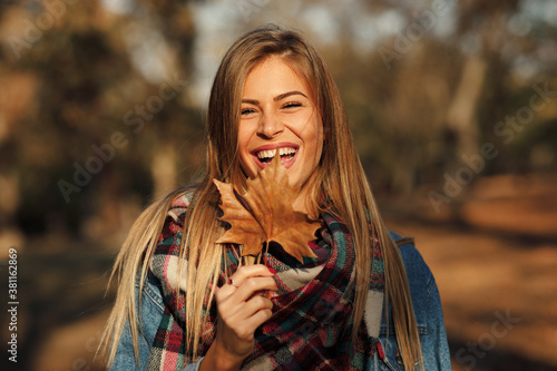 Fotografía Portrait of a beautiful blonde with a smile on face holding a leaf in hand in th