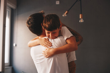 The father holds his son in his arms, they are in the living room, the family moment