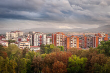 Autumn Colors Of Foreground Trees, Doft Light On Old Buildings And Dramatic, Blue Hour Sky Above Pirot Cityscape